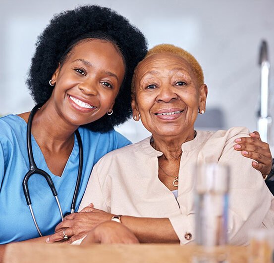 young black female medical professional sitting with older bald black woman